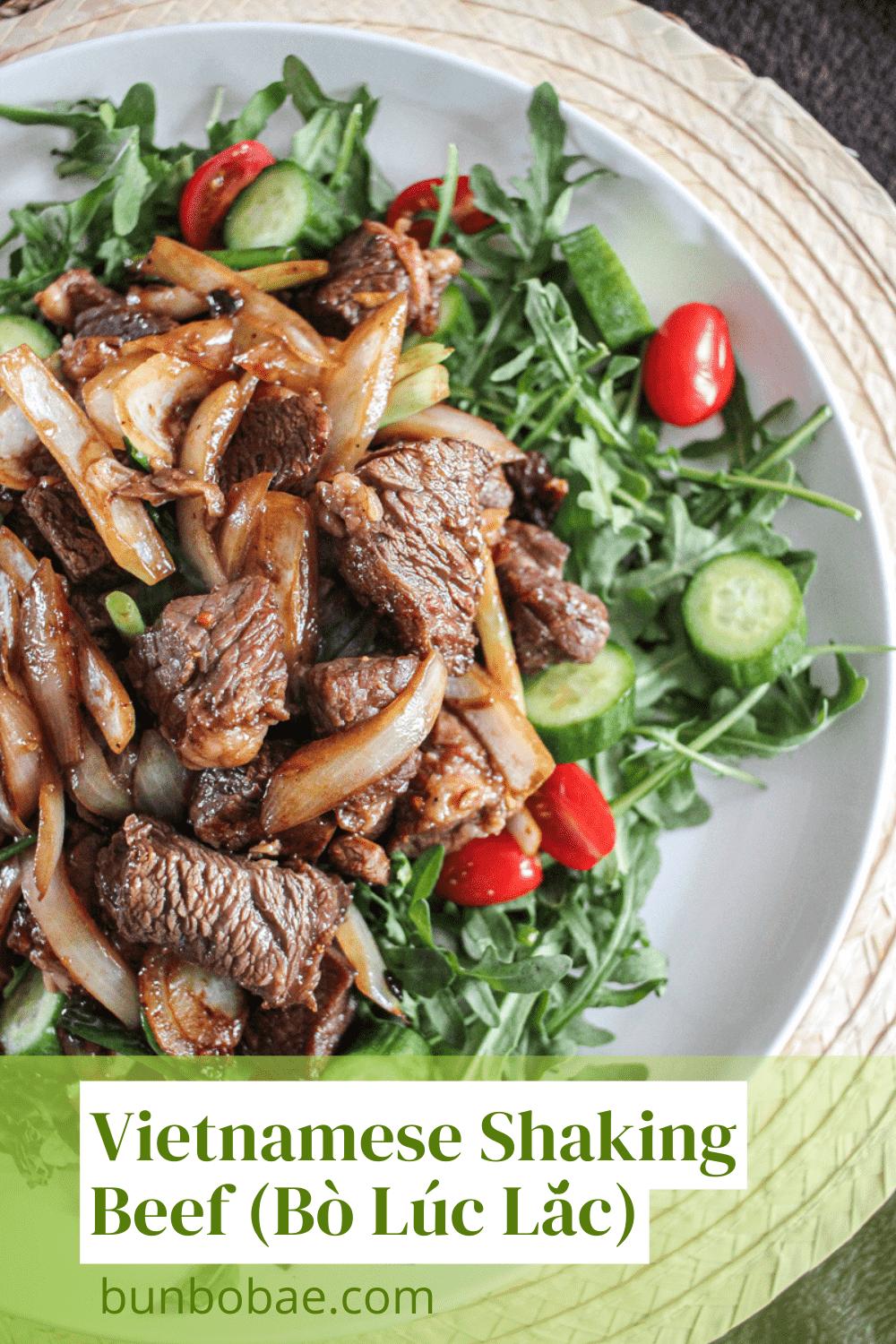 A birds eye view of Bò Lúc Lắc on a bed of arugula, tomato and cucuber