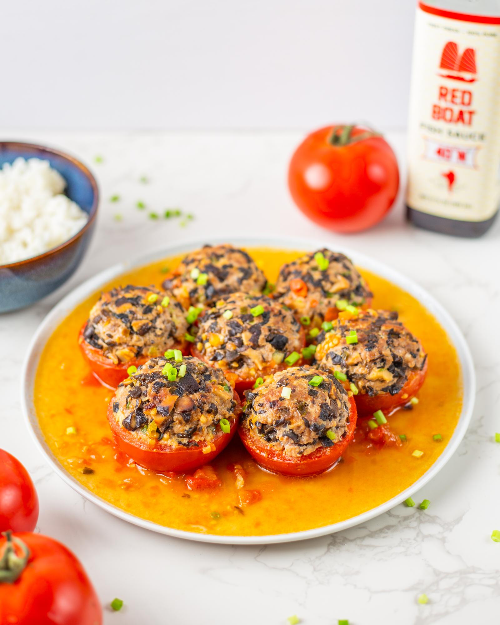 White plate with 7 halves of tomatoes-stuffed with a mixture of pork and mushrooms; panfried and simmered in tomato sauce.